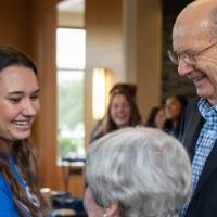 A Thompson Scholar smiling while meeting with Robert and Ellen Thompson.